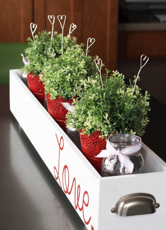a stylish centerpiece in a box with red lace pots, greenery and wire hearts in the pots