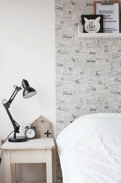 The headboard wall is enlivened with newspaper like wallpaper