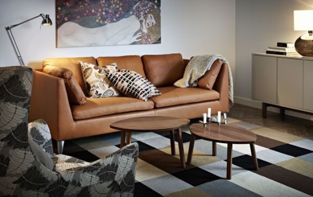 a cozy living room with a tan leather Stockholm sofa and a printed rug