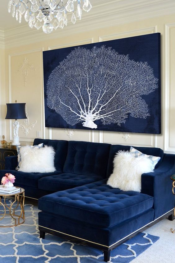 a navy artwork with a coral perfectly matches the sofa and hints on the ocean location of the home