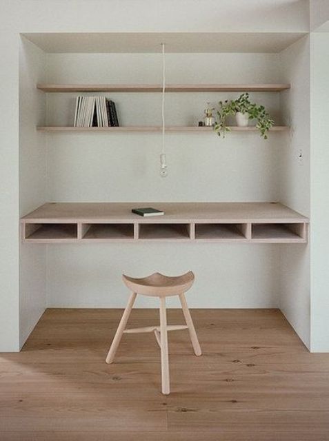 A built in workspace with floating shelves and a comfy desk with storage inside