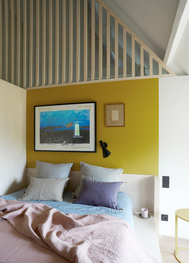 The guest bedroom is colorful, with a bold wall and bedding plus comfy furniture