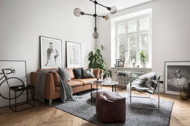 An airy and light filled Nordic space with a tan leather sofa and ottoman looks wow
