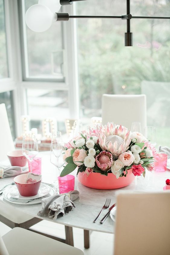 stylish Valentine's day table decor with pink bowls, glasses and a pink bowl centerpiece with lush florals