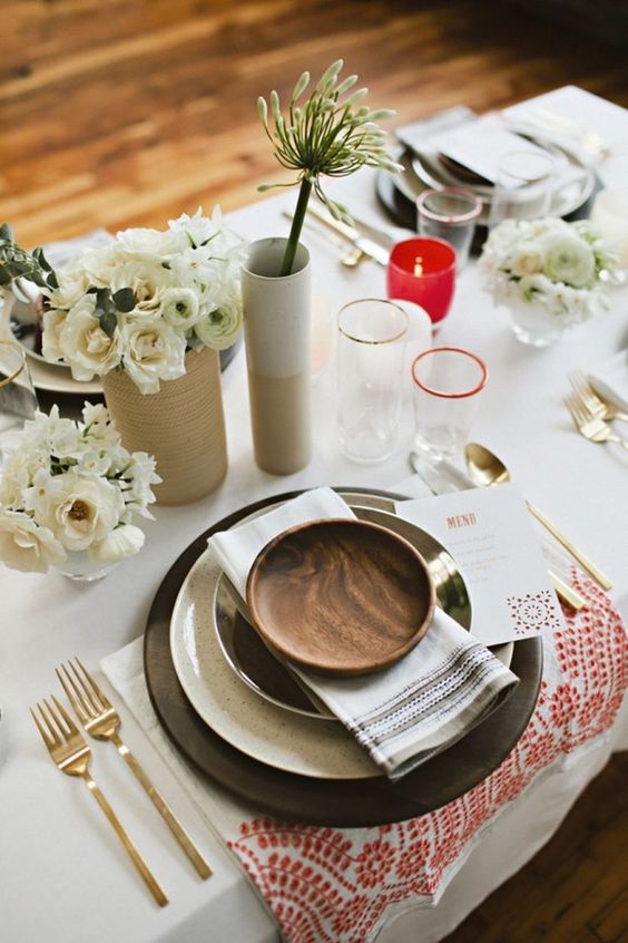 simple table decor with black chargers, neutral florals and red candle holders
