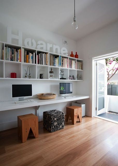 a modern shared space with floating bookshelves and a floating desk plus stools