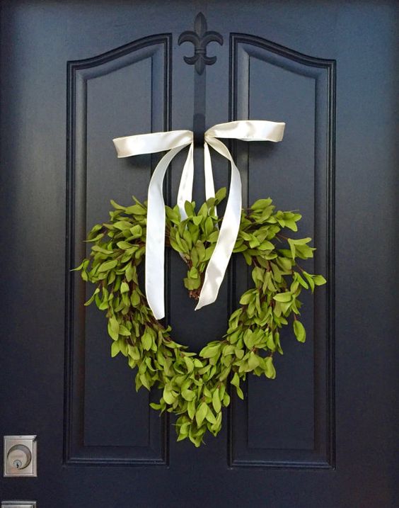 a boxwood heart wreath with a ribbon bow to decorate the front door