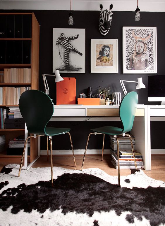 a moody workspace with a black wall, emerald chairs and a couple of Micke desks