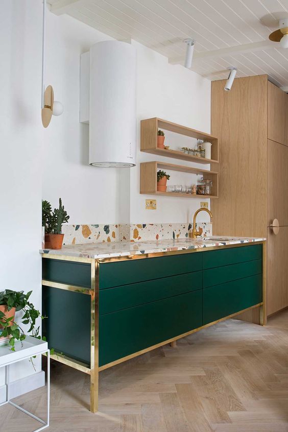 an emerald cabinets with brass framing and a terrazzo countertop for a bold and chic look