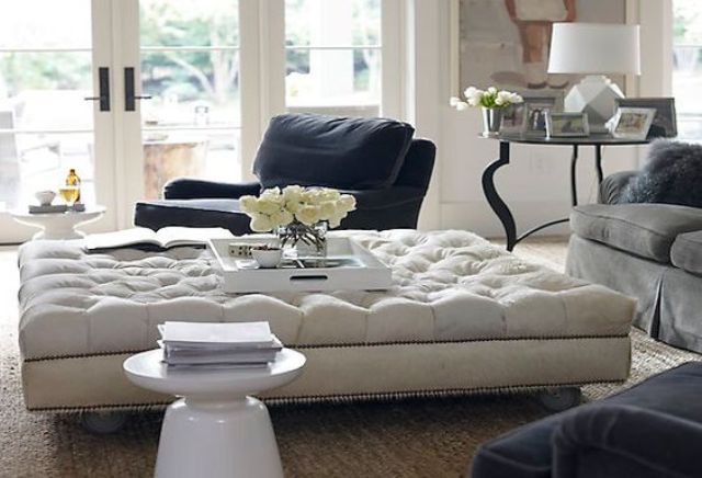 an oversized tufted ottoman adds a refined touch to the space and works as a coffee table
