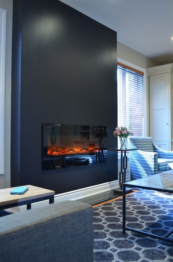 A black accent wall with a built in fireplace for a cozier feel