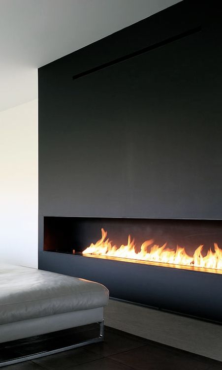 a long, horizontal fireplace clad with dark metal looks ultra-minimalist