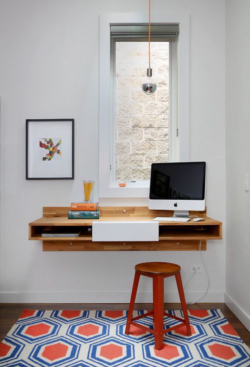 a floating mdi-century modern desk with storage space inside and a matching metal stool