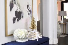 22 an oversized artwork plus a matching navy and gold entryway bench are a chic combo
