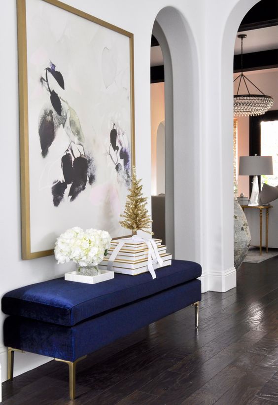 an oversized artwork plus a matching navy and gold entryway bench are a chic combo
