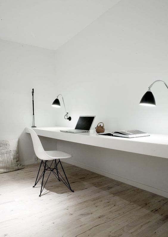 a minimalist workspace with a floating desk, lamps and a modern chair