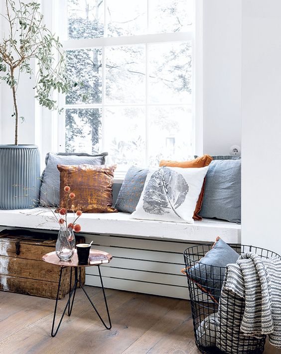 a thick windowsill seat with lots of pillows and a coffee table by its side