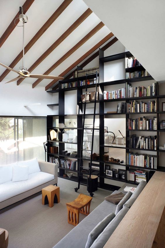 the ceiling is acctuated with faux beams and a large and tall bookcase