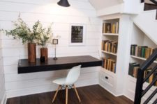 26 a small attic workspace with a dark-stained floating desk and built-in bookshelves