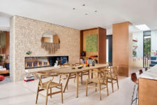 01 The dining space features a faux brick wall with a double-sided fireplace and a light-colored wooden dining set