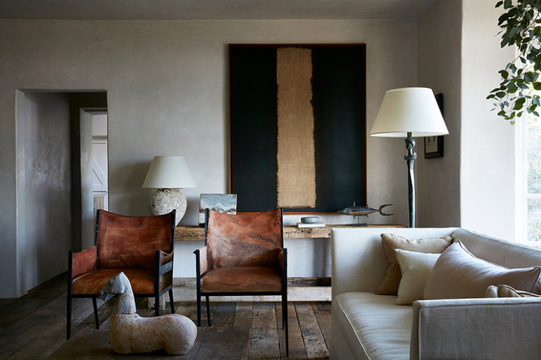 The living room is done in neutrals, with some leather chairs, a gorgeous statement artwork, a unique statuette