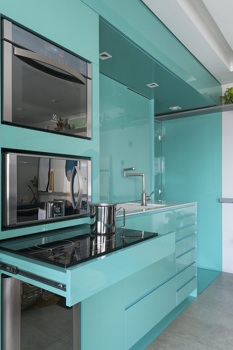 Sleek green surfaces make the kitchen stand out and visually separate this utility zone from the rest of the space