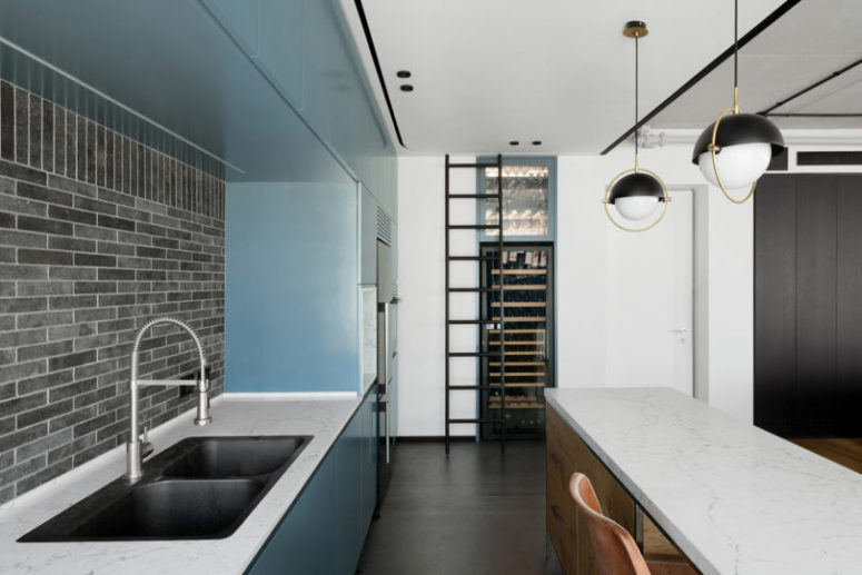 The kitchen includes blue cabinet, a large wine cooler and a kitchen island with a breakfast space