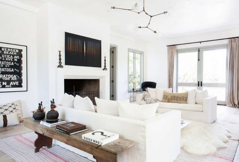 The living room is a gorgeous large space filled with whites and light, a fireplace and some rustic touches that add coziness