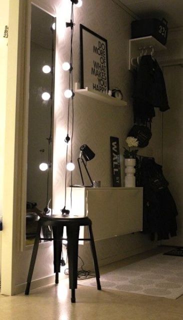 a string of lights accents the narrow wall mirror and adds light to the small space