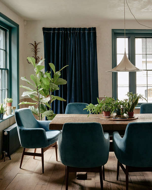The dining room shows off dark green and blue accents with light colored and warm colored wood