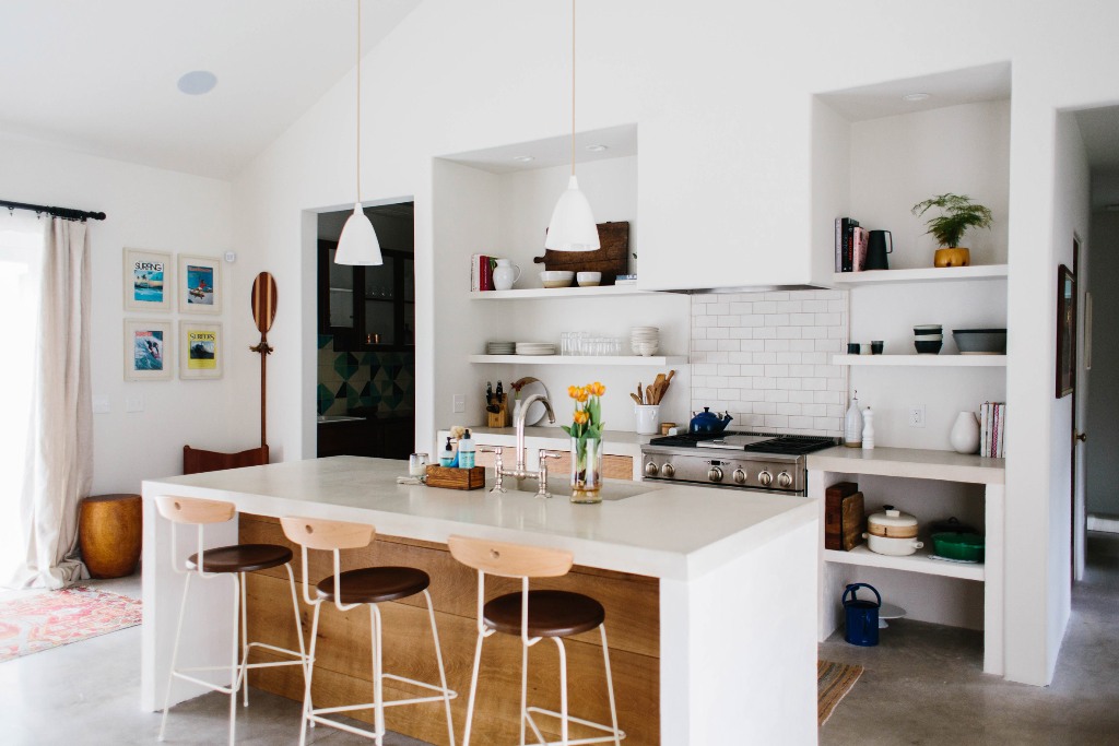 The kitchen is done in white, with a subway tile backsplash, a white kitchen island and countertops