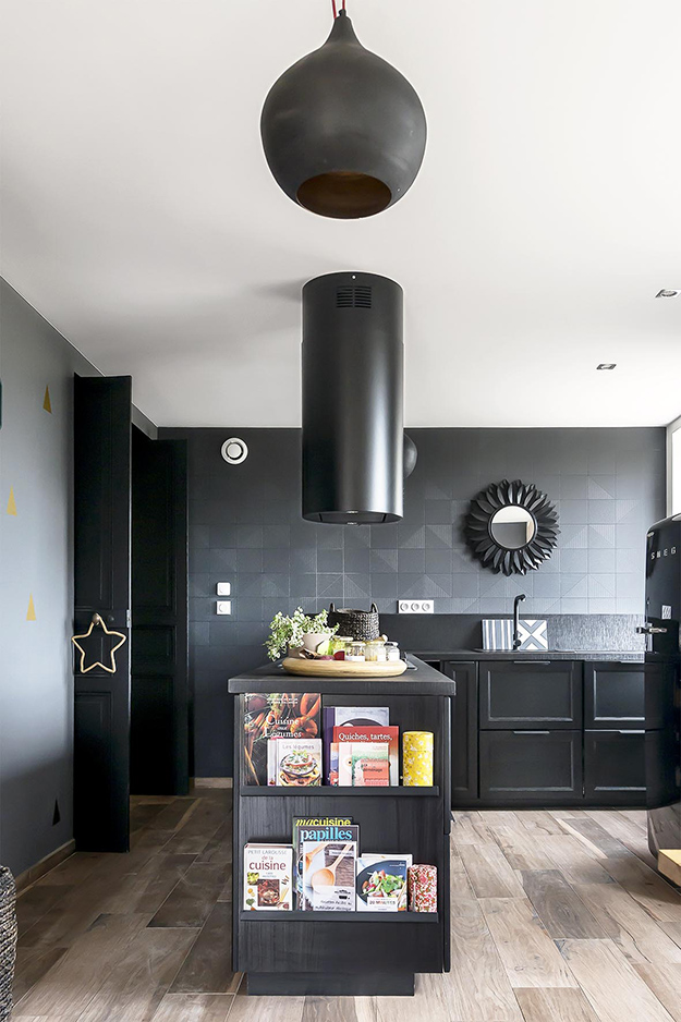 The kitchen is done with a lot of black - black walls, tiles, appliances, cabinets