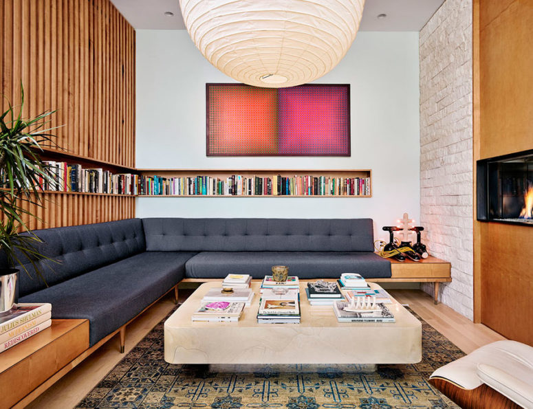 The living room is done with a large corner sofa, a built-in bookshelf and is centered around the fireplace
