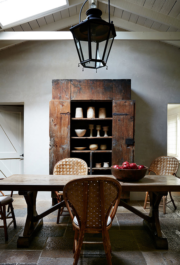 The dining space shows off a fantastic antique weathered cupboard, some woven chairs and a rustic dining table