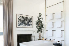 05 The master bathroom is a gorgeous space with a fireplace, blush curtains, artworks and potted plants
