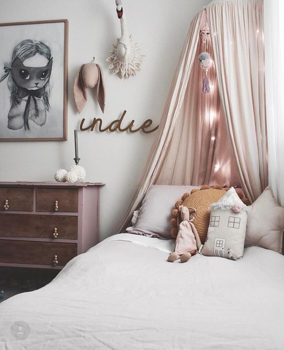 a blush bed canopy with some string lights inside to make the sleeping nook welcoming