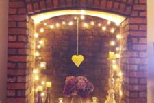 05 a fireplace with string lights, a hanging heart and some candles for a cute look