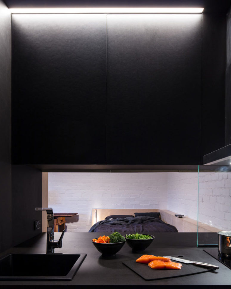The kitchen is all-black and features a pass through window to the room to make eating and having drinks comfier