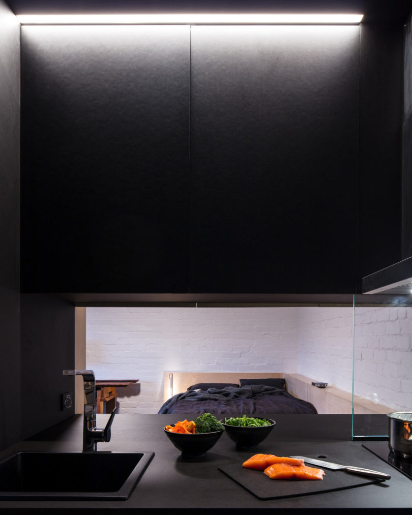The kitchen is all black and features a pass through window to the room to make eating and having drinks comfier