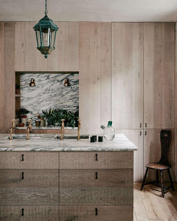 The kitchen is clad with untreated wood, there are elegant marble and brass accents