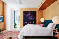 06 The master bedroom is done with light-colored wood, an upholstered wall and a very bold artwork that catches an eye