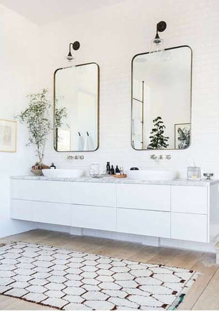You can also see a floating vanity with a marble top, two mirrors and a cozy rug
