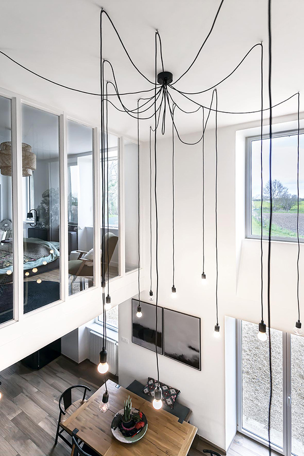 A modern and industrial chandelier highlights the height of the ceiling and brings more light to the bedroom above