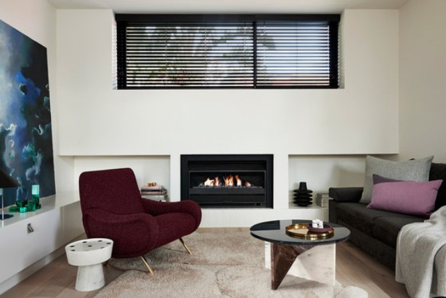 The living space is done with a comfy chair and sofa, a bold table on geometric stone legs and a built in fireplace