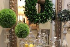 07 moss topiaries, a boxwood wreath with burlap, a greenery covered mirror and some lemons in a jar
