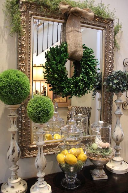 moss topiaries, a boxwood wreath with burlap, a greenery covered mirror and some lemons in a jar