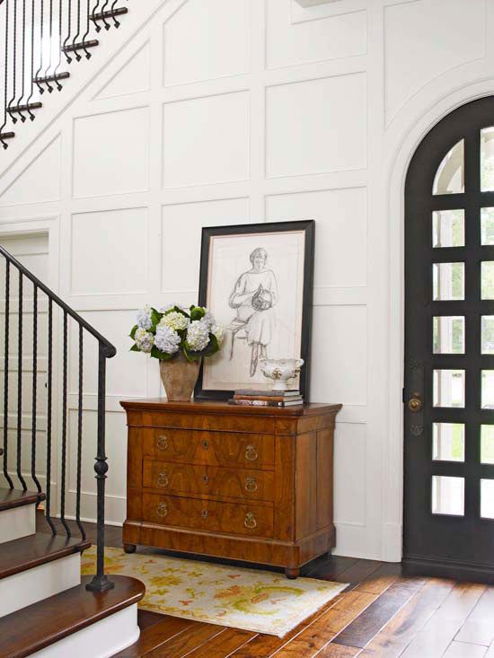 this entryway is spruced up with moldings on the walls and an antique sideboard