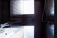 08 The bathroom is clad with black tiles and red grout for a stylish masculine-inspired look