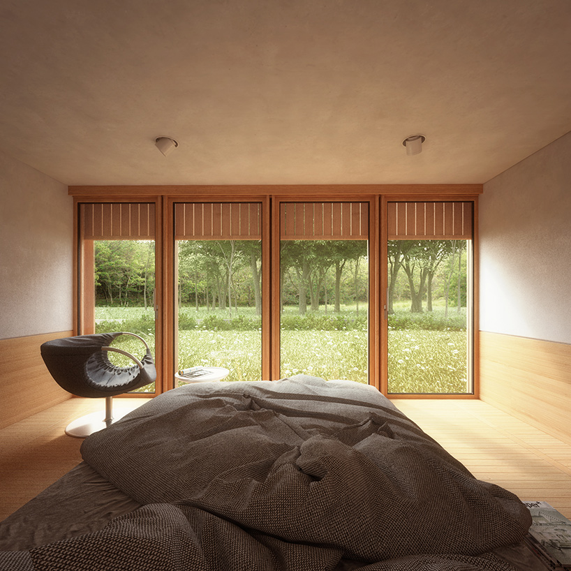 The bedroom features a large bed and a comfy chair, the window overlooks the woodland