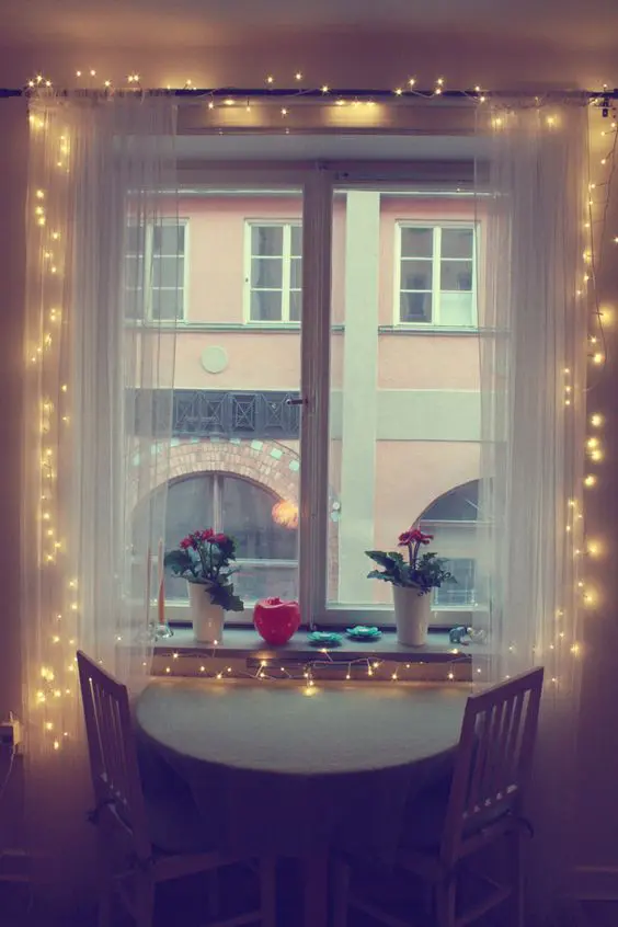 a little breakfast nook becomes inviting with sheer curtains and string lights inside them